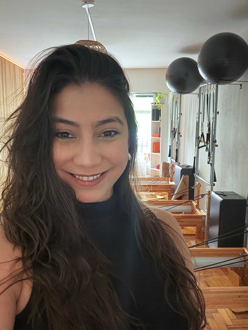 Betiana González sonriendo en su estudio, con los reformers de fondo