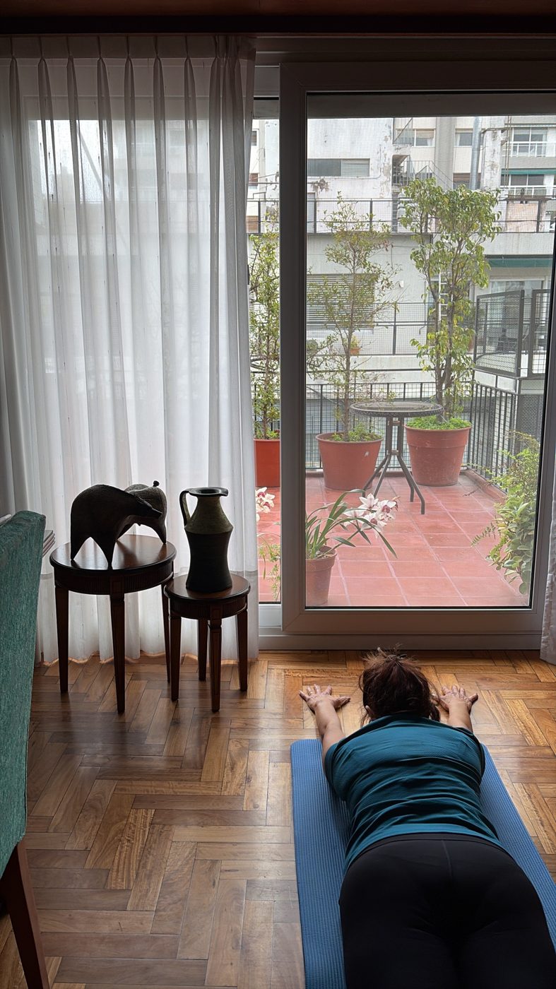 Alumna estirando sobre su colchoneta frente al ventanal de su casa